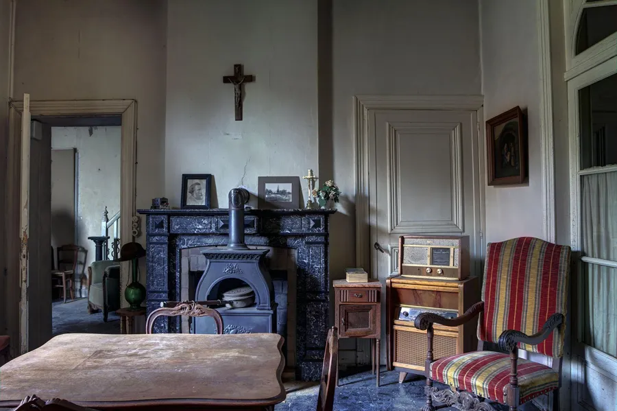 Salle à manger avec table, fauteuil rayé, radio et cheminée