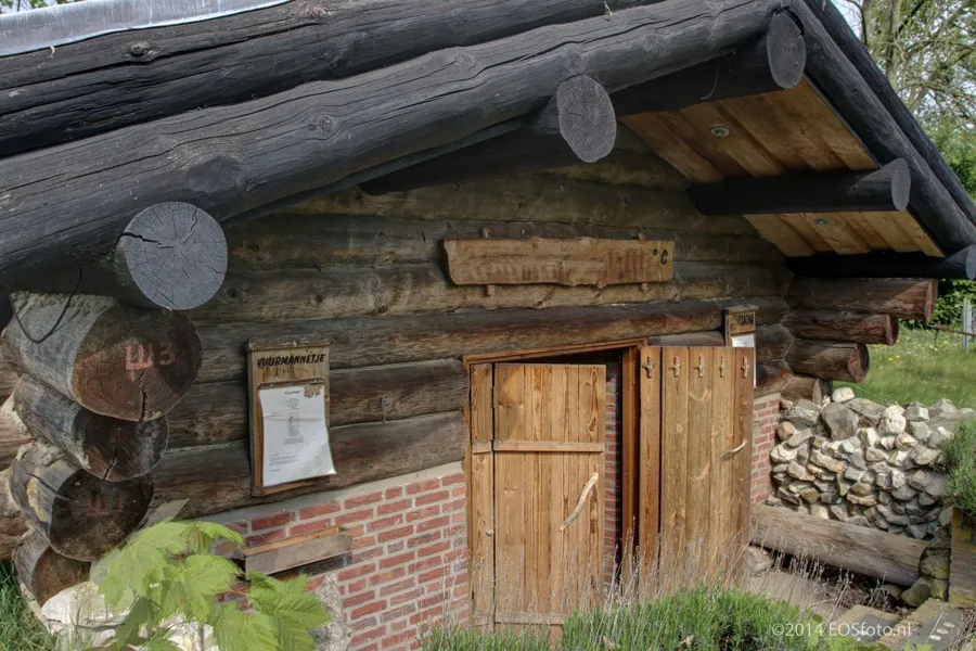 Sauna exterior baja de madera con puerta doble y base de ladrillo.