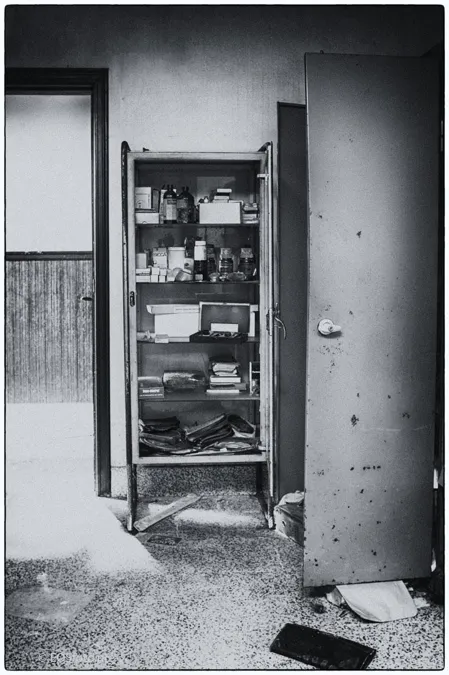 Fotografía en blanco y negro de un armario abierto con frascos y cajas