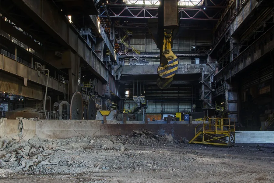 Crane hook above rubble and a low concrete wall inside the hall.