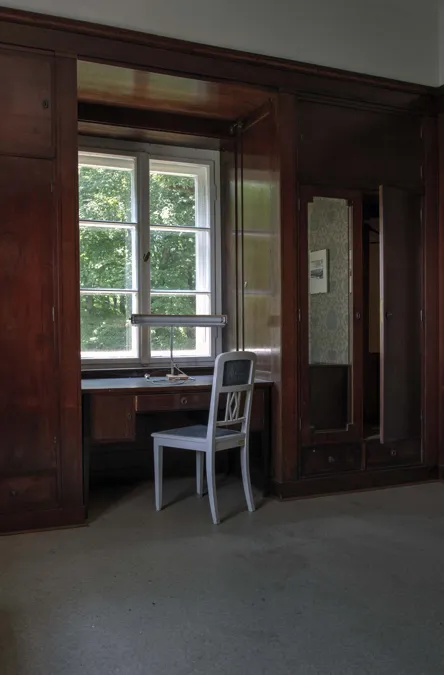 Stoel bij een bureau onder een raam met uitzicht op bomen