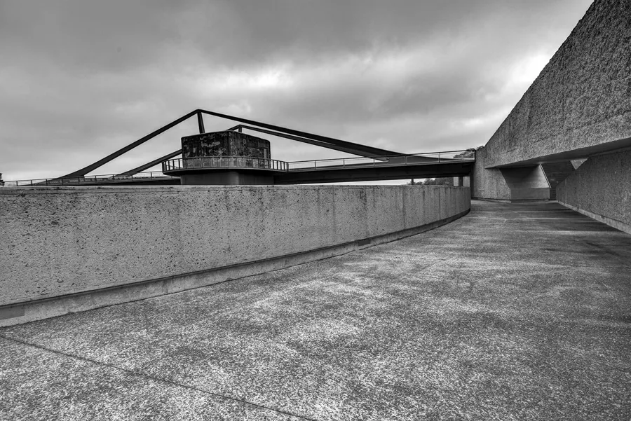 Zwart-witfoto langs een betonnen hellingbaan, met een lage bunker en schuine brugliggers achter de borstwering.