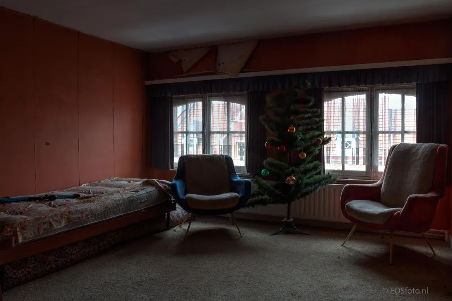 Two armchairs beside a bed and decorated Christmas tree.