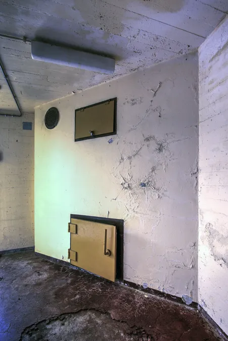 Lege witte kamer met ronde luchtopening en twee kleine gele wandluiken.