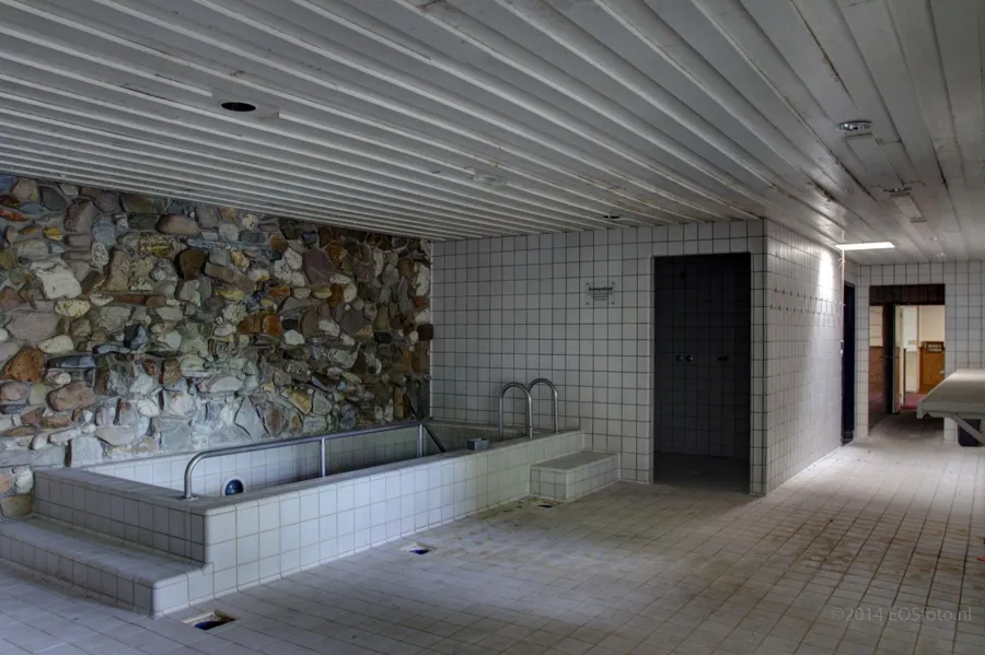 Piscina rectangular de inmersión junto a una pared de piedra rugosa.