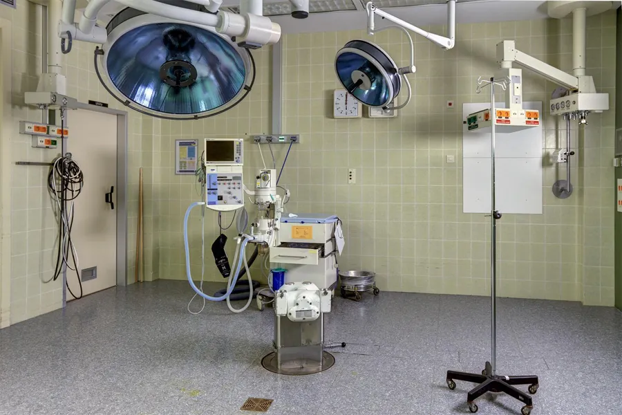 Operating room with blue lights, medical equipment and an empty IV stand.