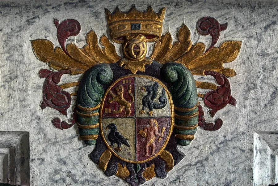 Escudo de armas de colores con corona sobre la chimenea
