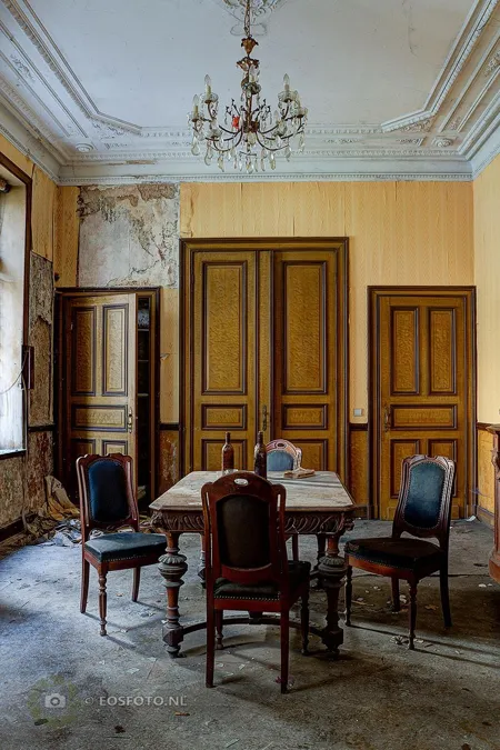 Eetkamer met kroonluchter, tafel en geel geschilderde deurpanelen