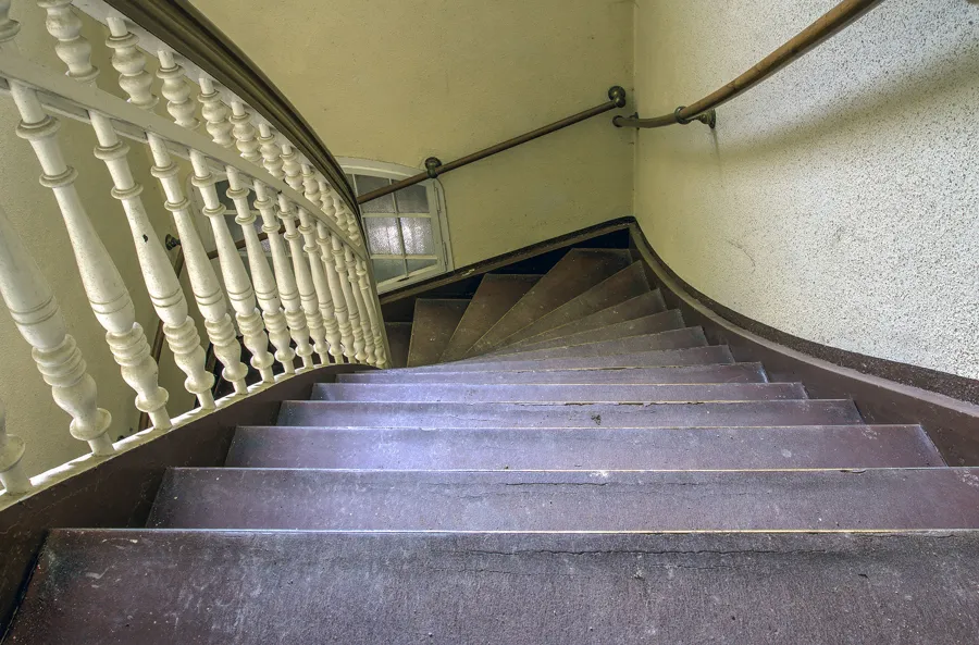 Gebogen houten trap met lichtgekleurde spijlenleuning