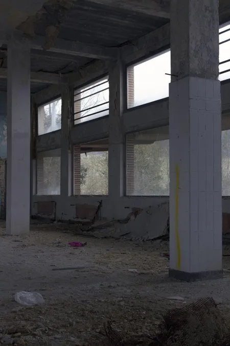 Leerer hoher Raum mit zwei Fensterreihen und Schutt am Boden.