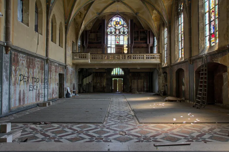 Chapelle vide avec tribune au fond et graffitis sur les murs