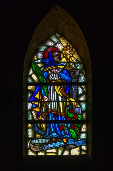 Spitzes Buntglasfenster mit religiöser Figur in Blau und Gelb.