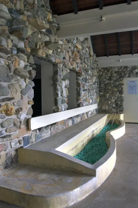 Estanque estrecho y curvo junto a una pared revestida de piedra.