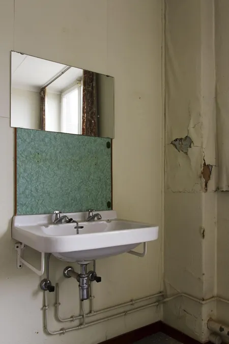 Dubbele witte wastafel onder een spiegel naast een raam.