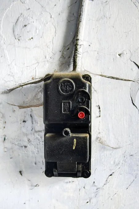 Alter schwarzer elektrischer Schaltkasten an weißer Wand
