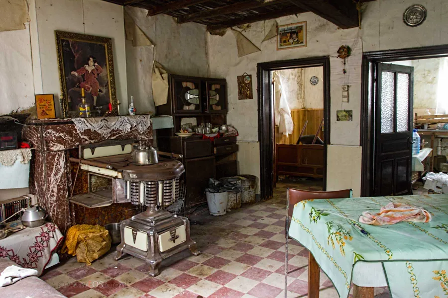Sala pequeña con estufa, mesa y vigas bajas de madera.