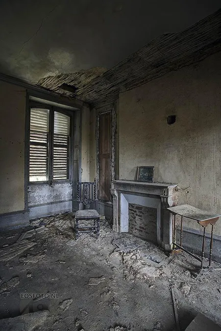 Empty room with fireplace, shutters and floor debris