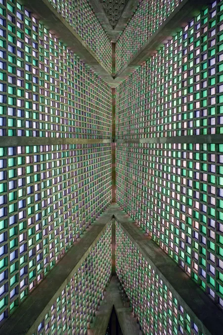 Vista ascendente por nervios de hormigón y bloques de vidrio de colores hacia la cumbrera.
