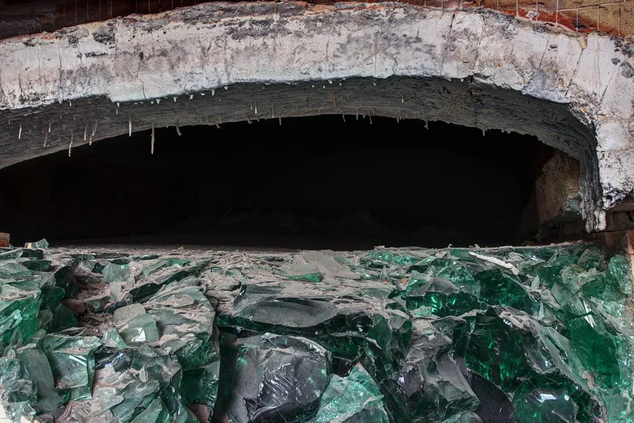 Donkere ovenopening boven grote stukken groen glas.