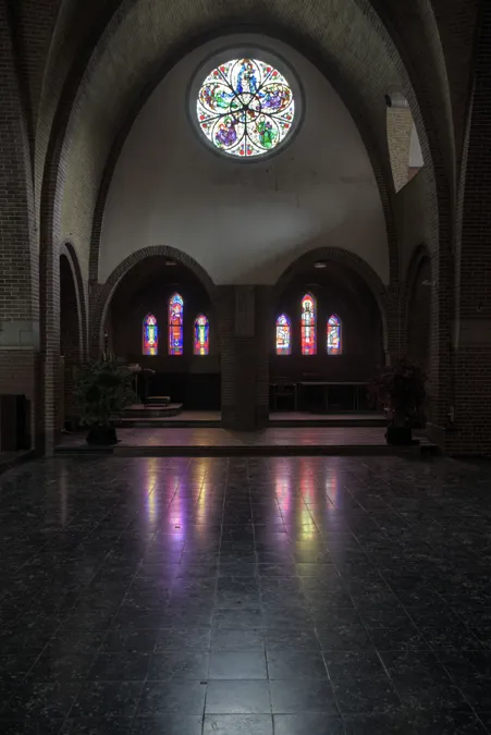Capilla con rosetón circular y reflejos de colores en el suelo oscuro.
