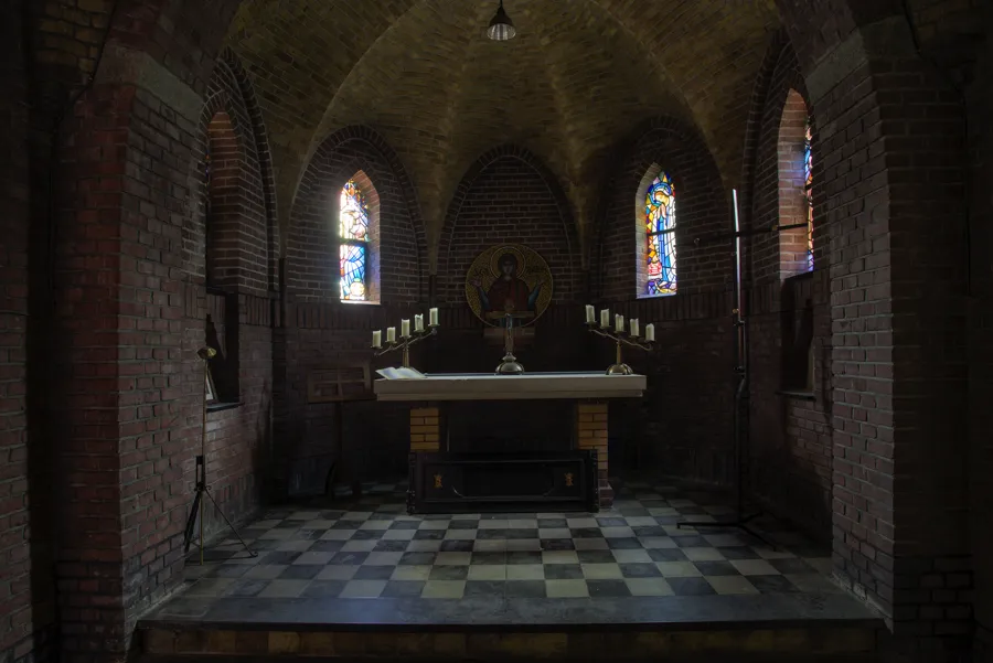 Altar pequeño bajo bóveda de ladrillo entre vidrieras.