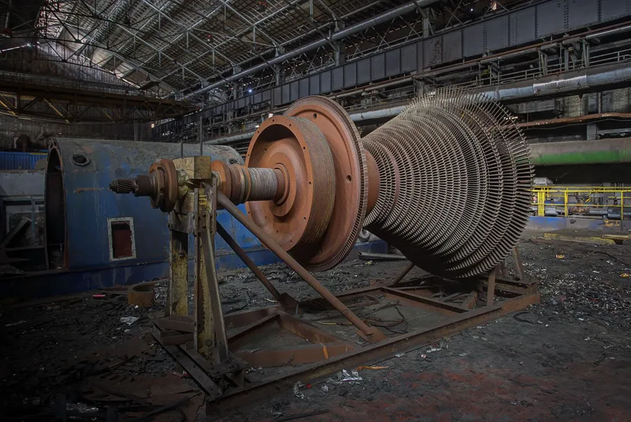 Rotor de turbine démonté aux nombreuses aubes sur supports métalliques.