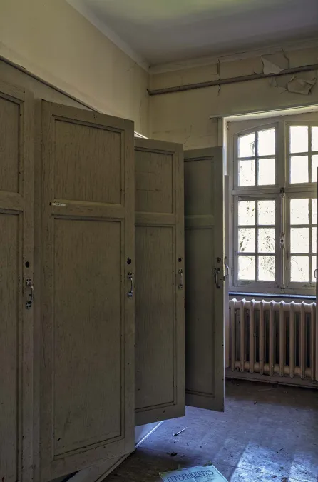 Porte d’armoire en bois ouverte près d’une fenêtre et d’un radiateur.