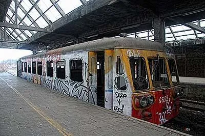 Old yellow-and-red railcar with graffiti inside the railway shed.