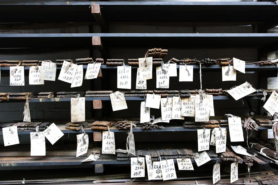 Barras metálicas con etiquetas manuscritas atadas en un estante.