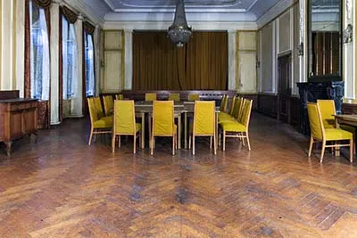 Comedor con mesa larga, sillas amarillas y suelo de parqué