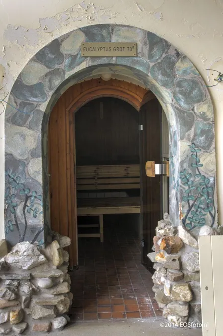 Puerta arqueada de sauna en una abertura enmarcada con piedras.