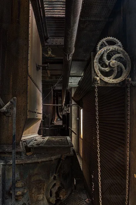 Handwheel with a hanging chain in a narrow dark plant space.