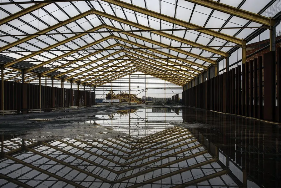 Groot leeg gebouw weerspiegeld in stilstaand water.