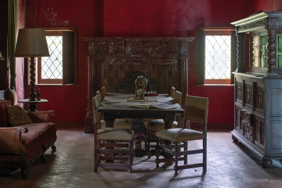 Comedor con paredes rojas, mesa, sillas y chimenea oscura