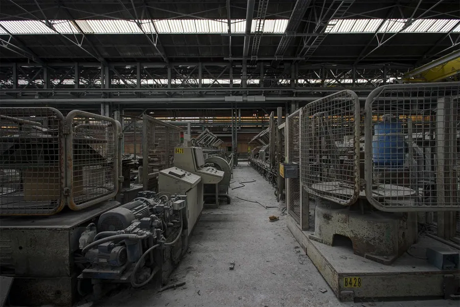 Smalle doorgang tussen machines met metalen beschermkooien.