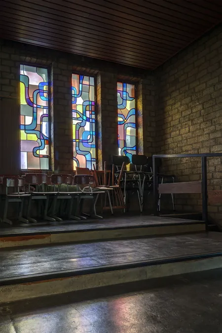 Narrow colourful windows above stacked chairs and dark steps.