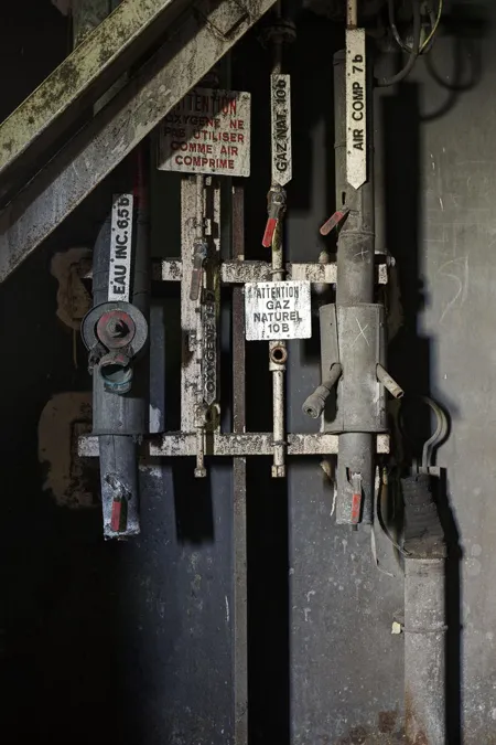 Oude hendels en afsluiters met labels aan een donkere wand.