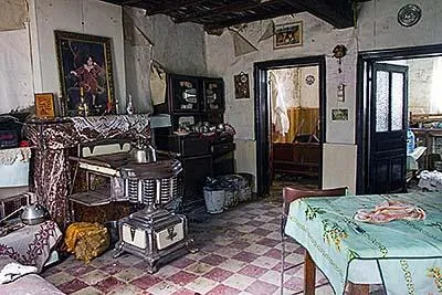 Sala pequeña con estufa, mesa y vigas bajas de madera.