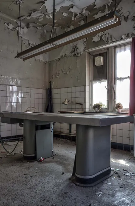 Table métallique sous une lampe suspendue dans une pièce au plafond écaillé.