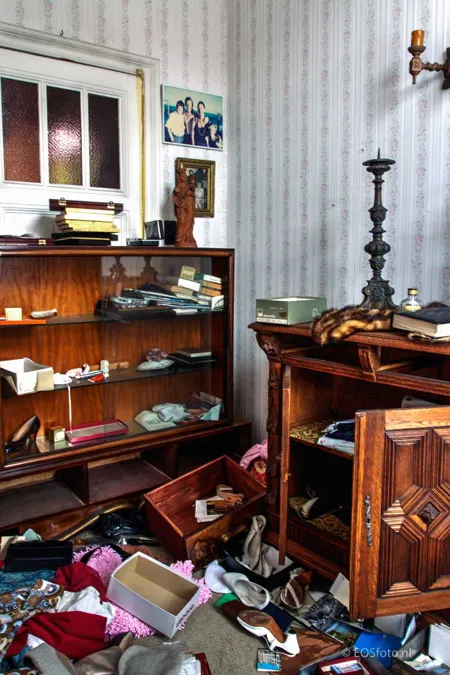 Open wooden cupboards among piles of papers and belongings.
