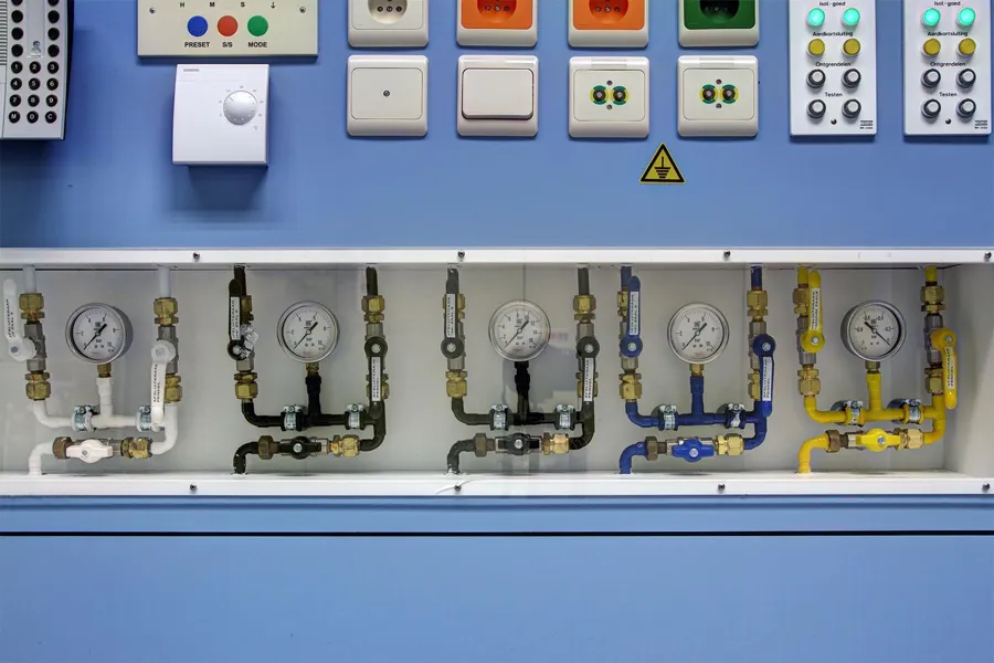 Coloured medical connections and pressure gauges behind an open panel.