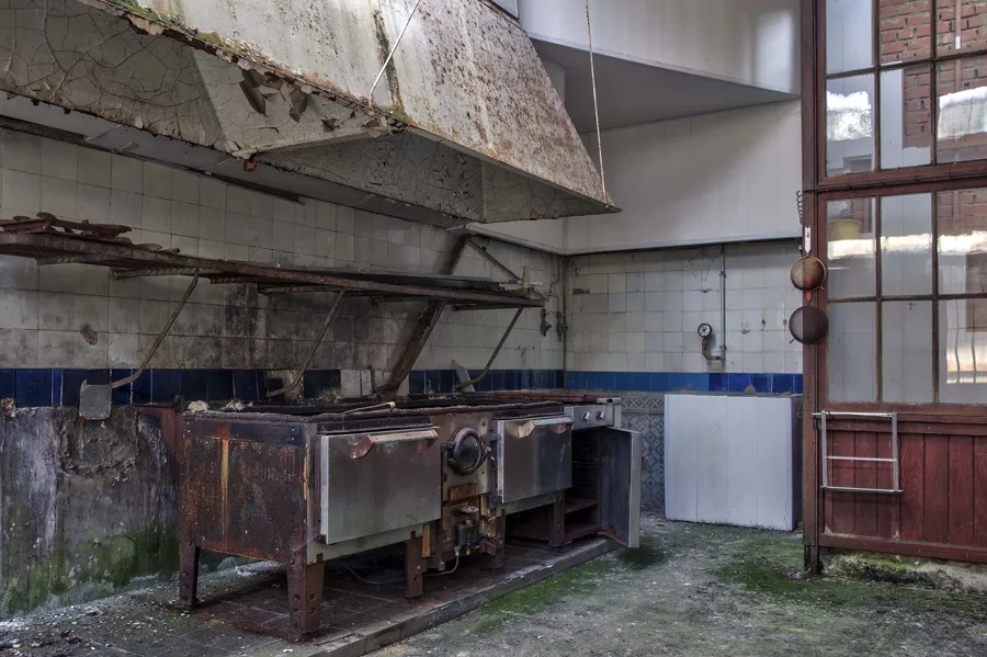 Old range beneath a large extractor hood in the hotel kitchen.