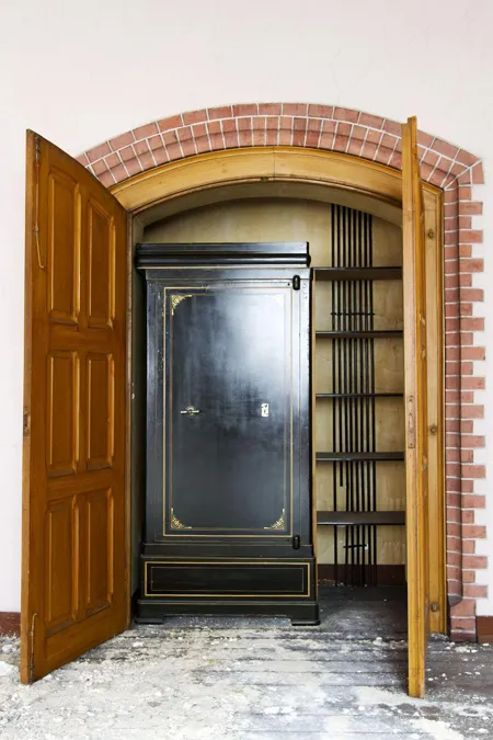 Open houten dubbele deuren naar een hoge zwarte kast en boekenplanken.
