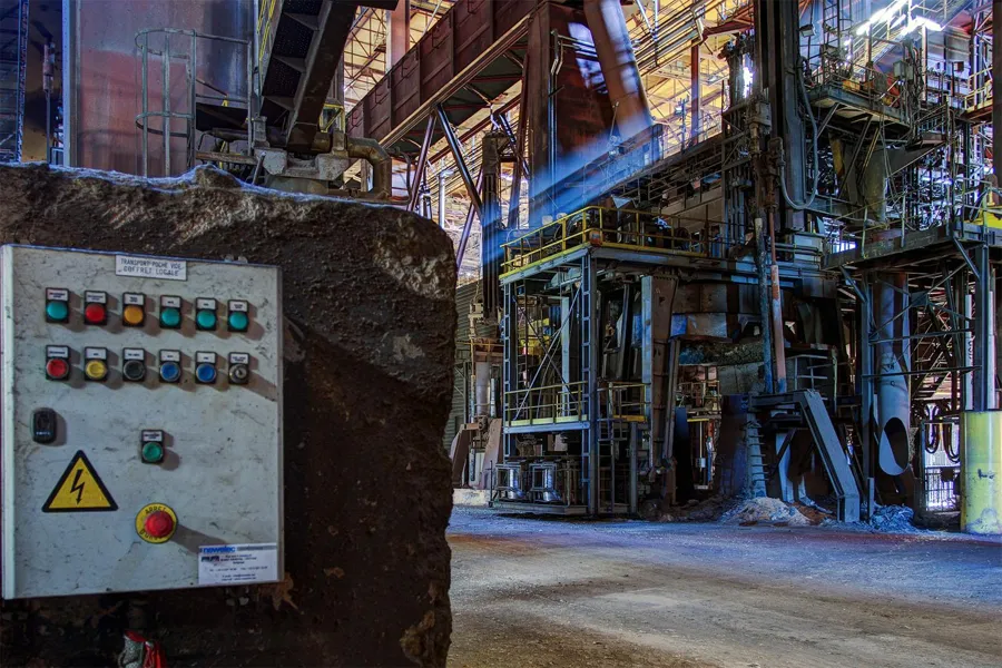 Control panel with coloured buttons before a large steelmaking installation.