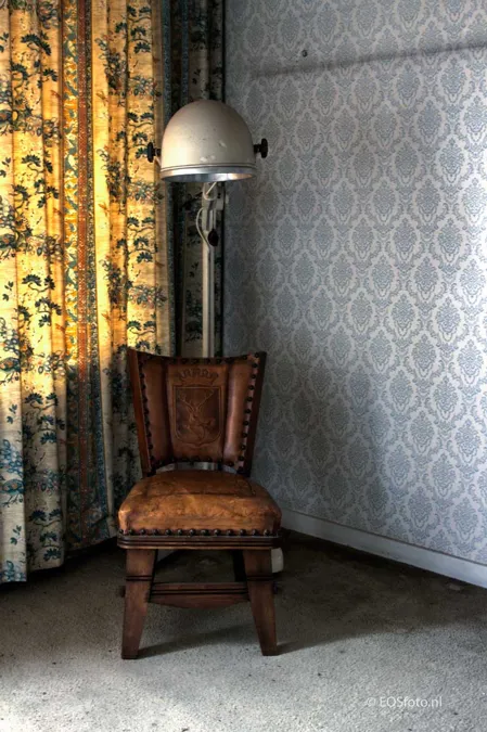Wooden chair beneath a large metal hood lamp.