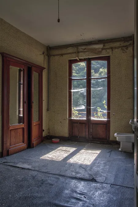 Empty room with wooden doors and sunlight on the floor.