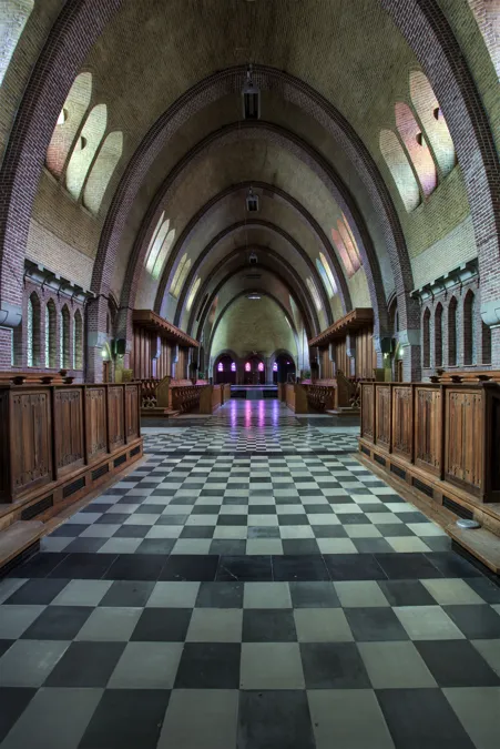 Vista frontal de capilla con sillería de madera y suelo ajedrezado.