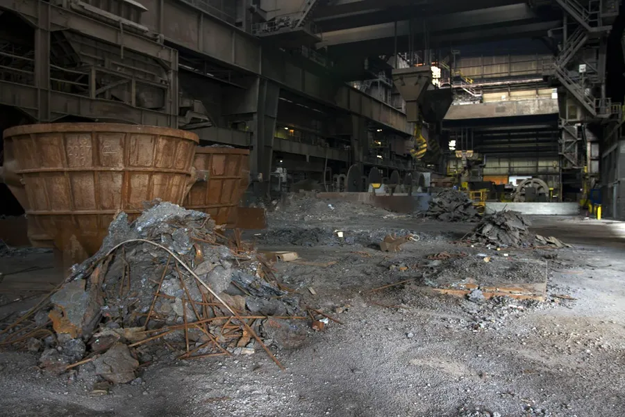 Large rusty vessels among rubble heaps in a factory hall.