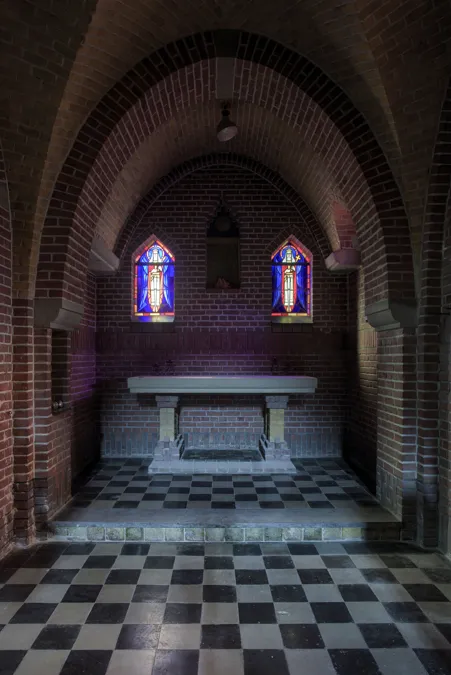 Altar de piedra blanca bajo bóveda de ladrillo con dos ventanas estrechas.