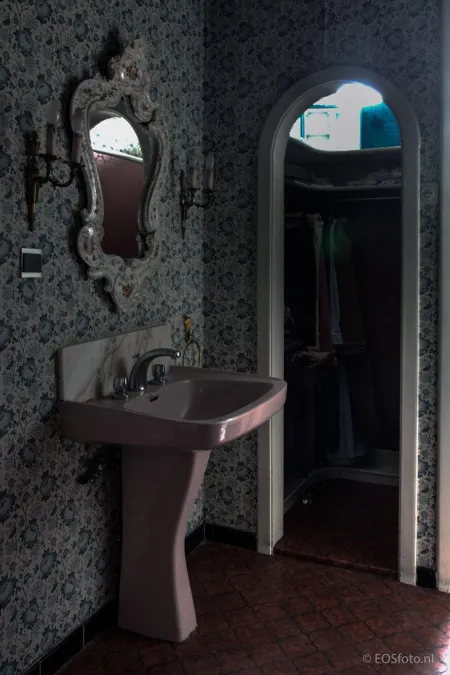 Pink washbasin and mirror beside an arched doorway.